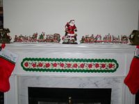 The fireplace mantle, with both beagle trains and a Santa figurine being hounded by 3 beagles